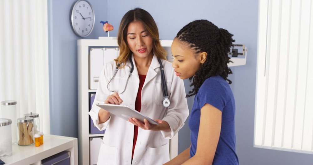Doctor shows young patient images on iPad in doctor's office
