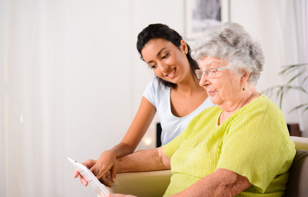 Woman explains medical options to older woman as she reads on with skepticism.