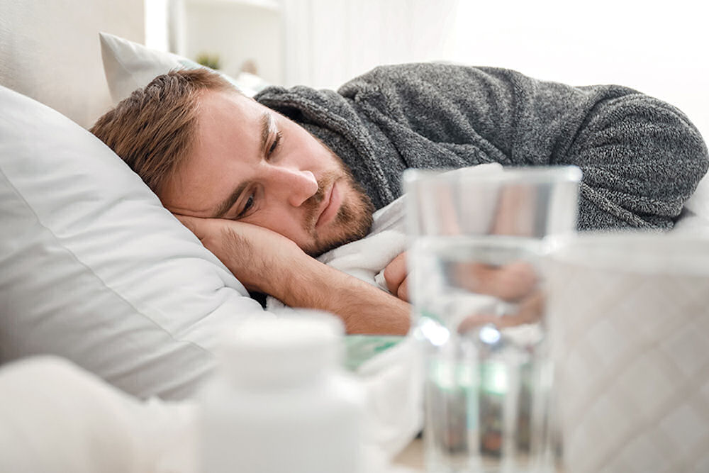Man with anxiety sleeps in bed with medication and glass of water on nearby nightstand.