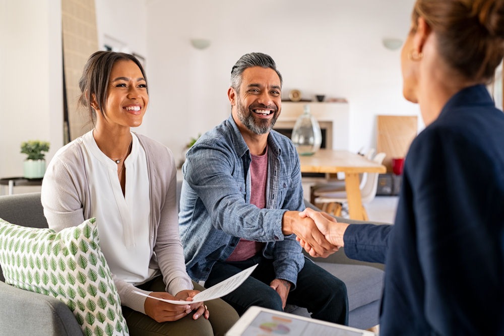 Smiling couple shaking hands with advisor after securing insurance for rehab treatment