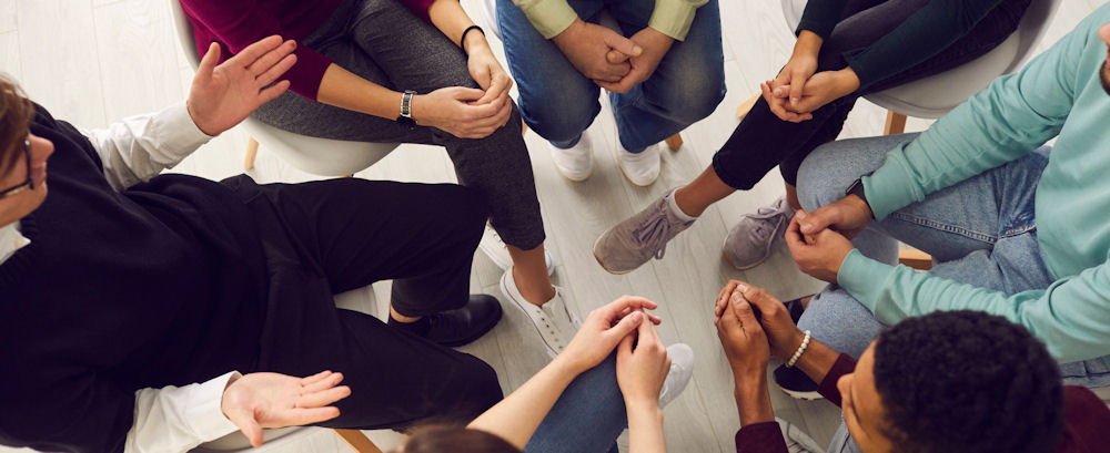 Overhead shot of LGBT group discussing addiction treatment.
