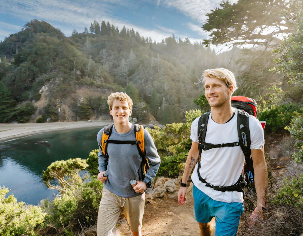 Two male college students taking a hike with backpack during a break from addiction treatment.