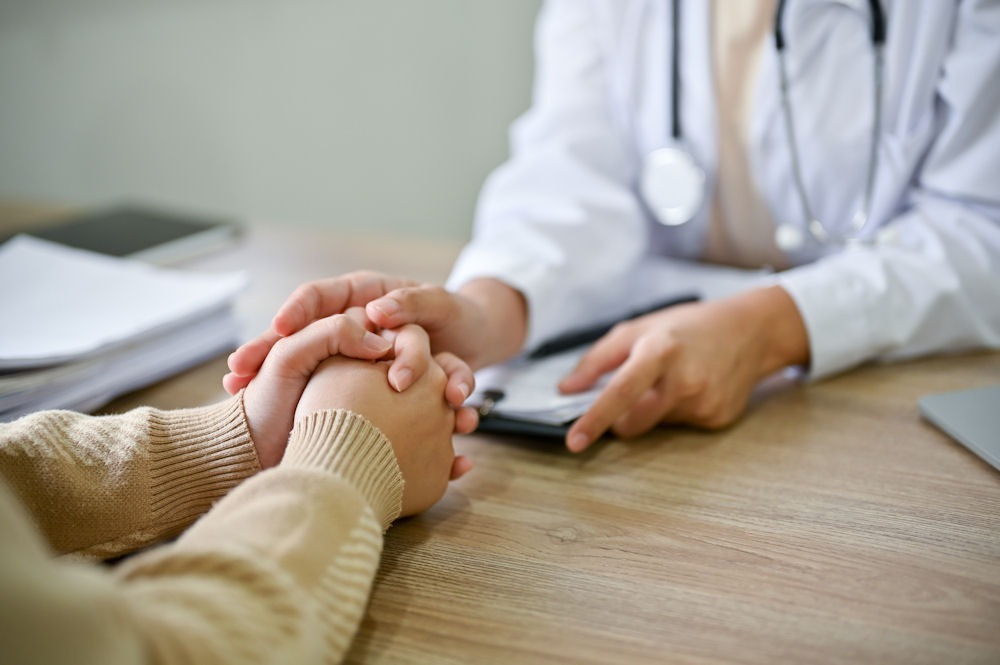 Doctor holding patient’s hands while explaining insurance coverage for rehab treatment