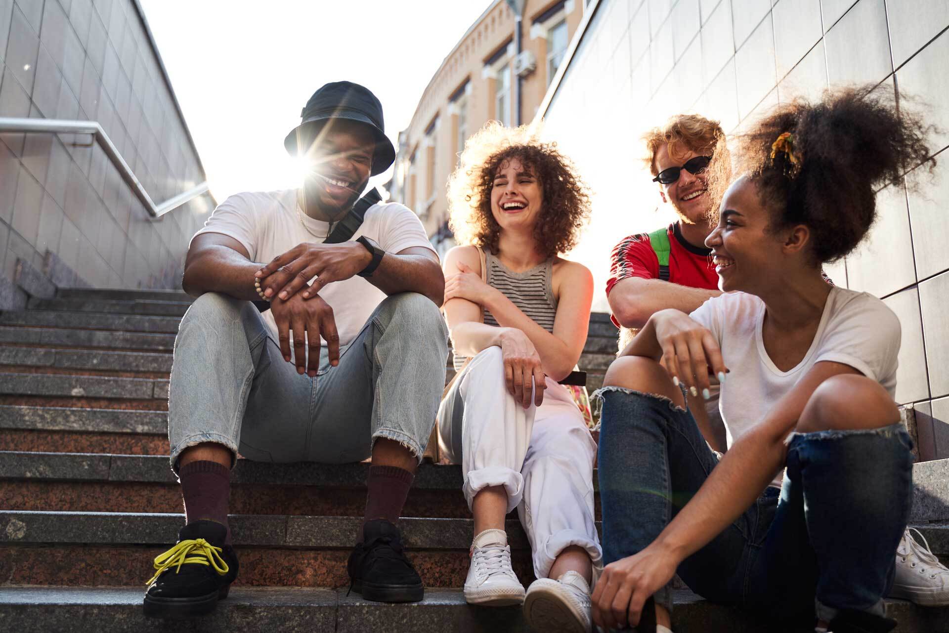Group of teens laughing while sitting on stoop