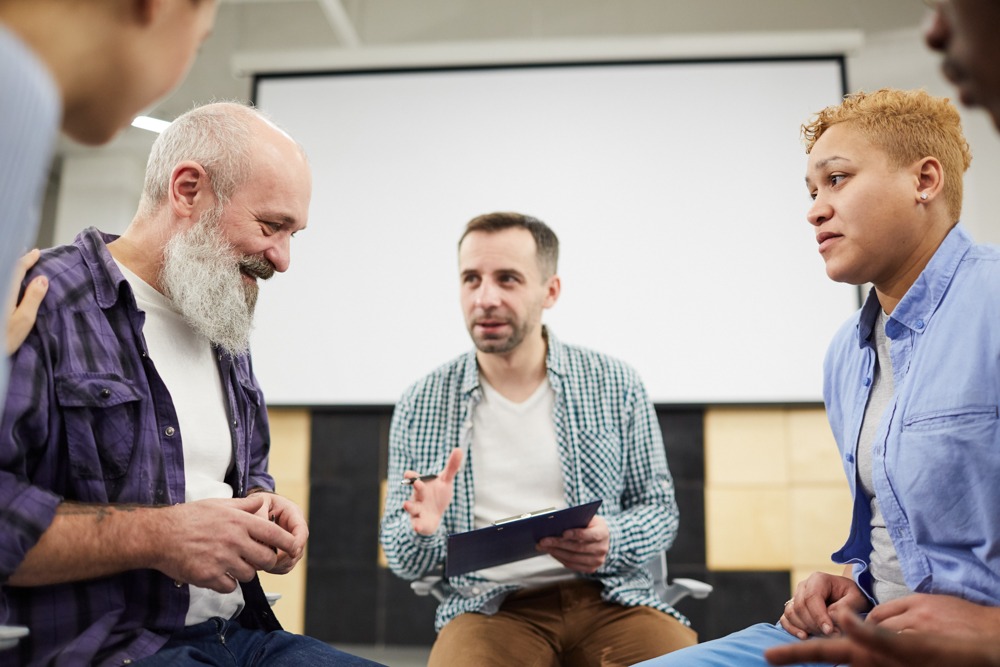 Health care professionals sitting in a circle discussing treatment for addiction and schizophrenia