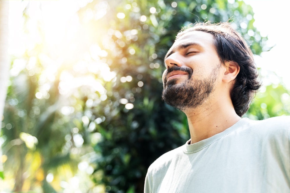 Man with OCD closing eyes peacefully outdoors.